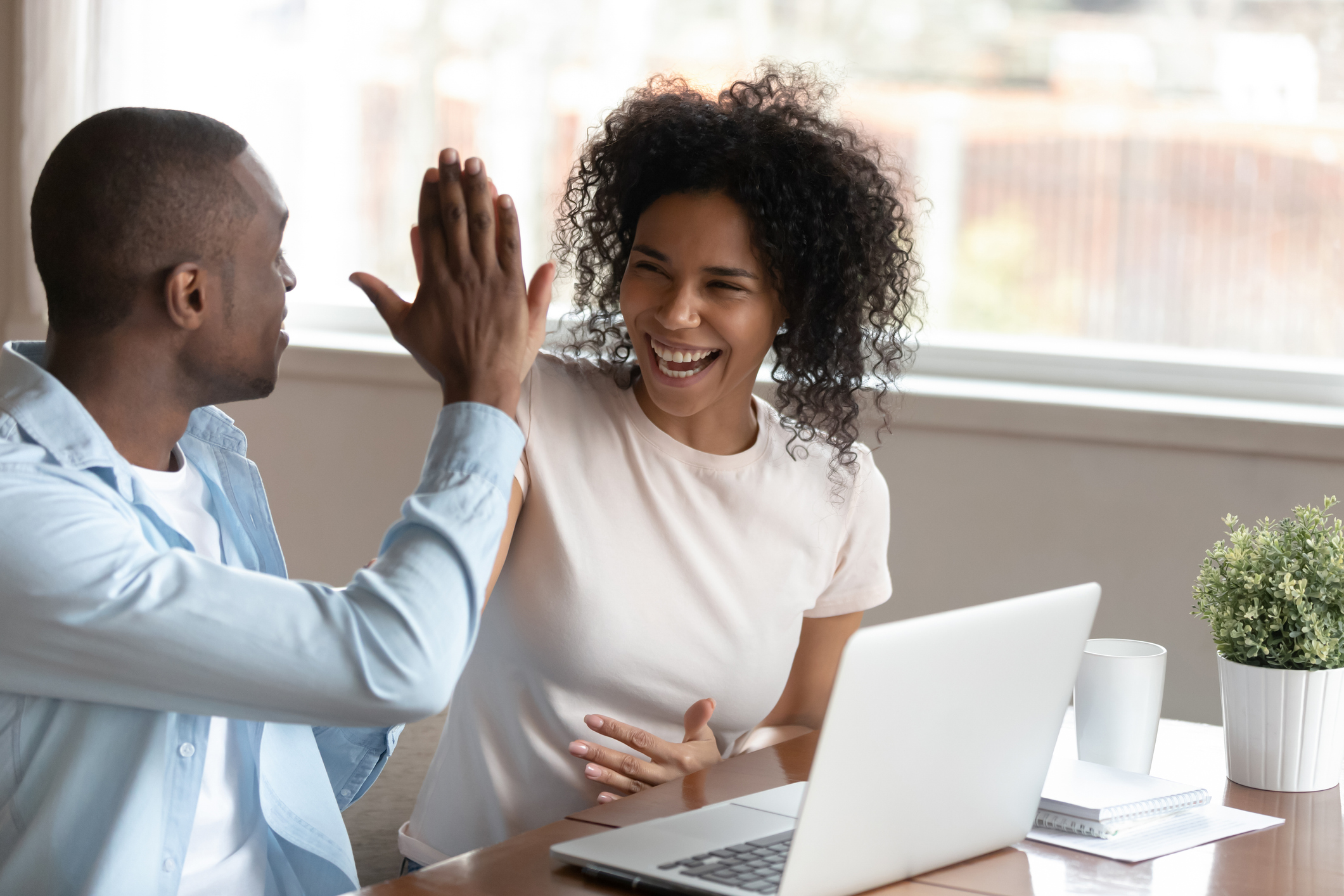 Happy couple high fiving over their finances